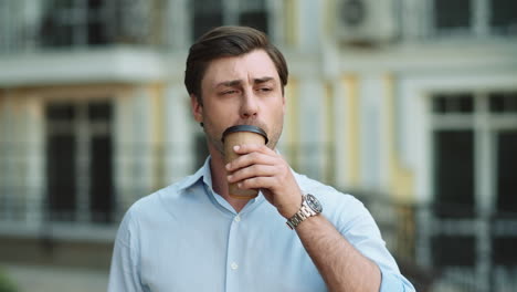 hombre de negocios en primer plano bebiendo café en la calle. hombre mirando lejos en la calle
