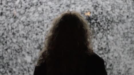 a silhouette of a woman in front of spinning snow flakes