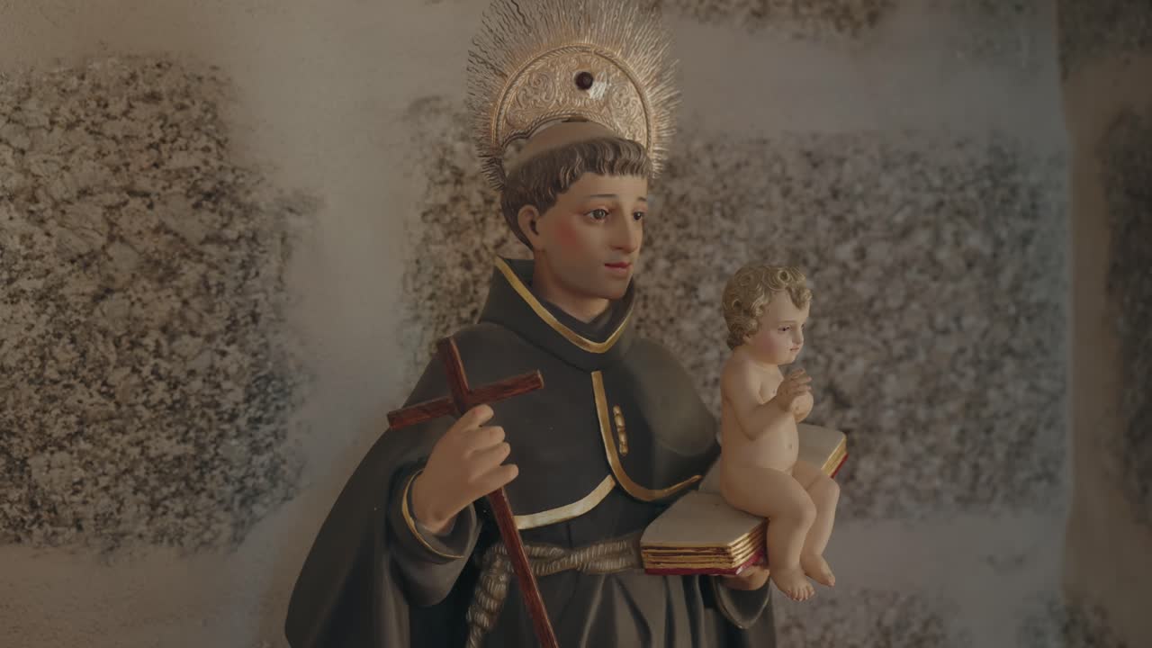 Reverent closeup of sacred saint sculpture holding infant and book in divine pose