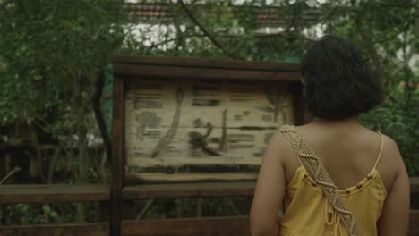 a young girl stands before an informational sign in the heart of an indian national park