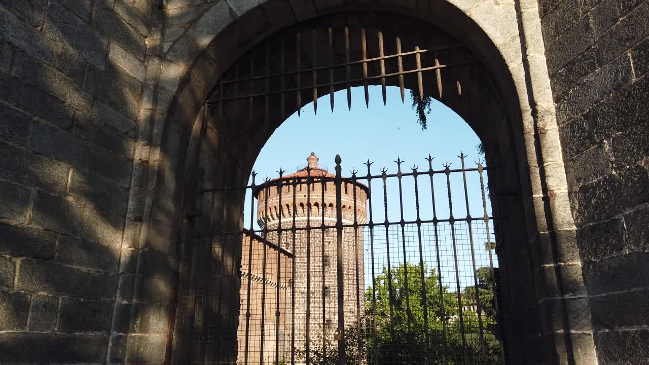 The Sforza Castle medieval fortification located in Milan , framed in arch gate door with warm afternoon light, tilt up view, historical city downtown