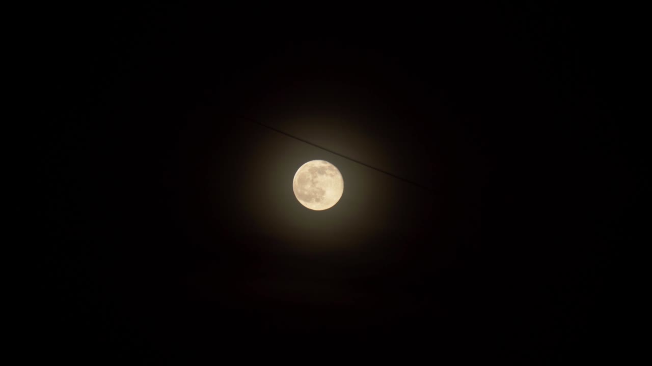 Close-up da lua cheia contra o céu noturno escuro. Fios elétricos, cidade à noite.