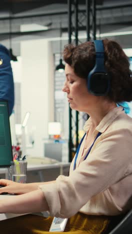 vertical video female executive consultant listening to songs on headphones at the workstation