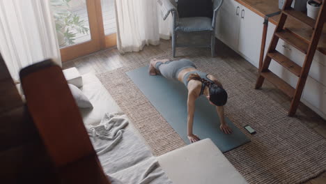 vista superior de una mujer asiática sana haciendo ejercicio en casa practicando flexiones en la sala de estar disfrutando del ejercicio físico matutino