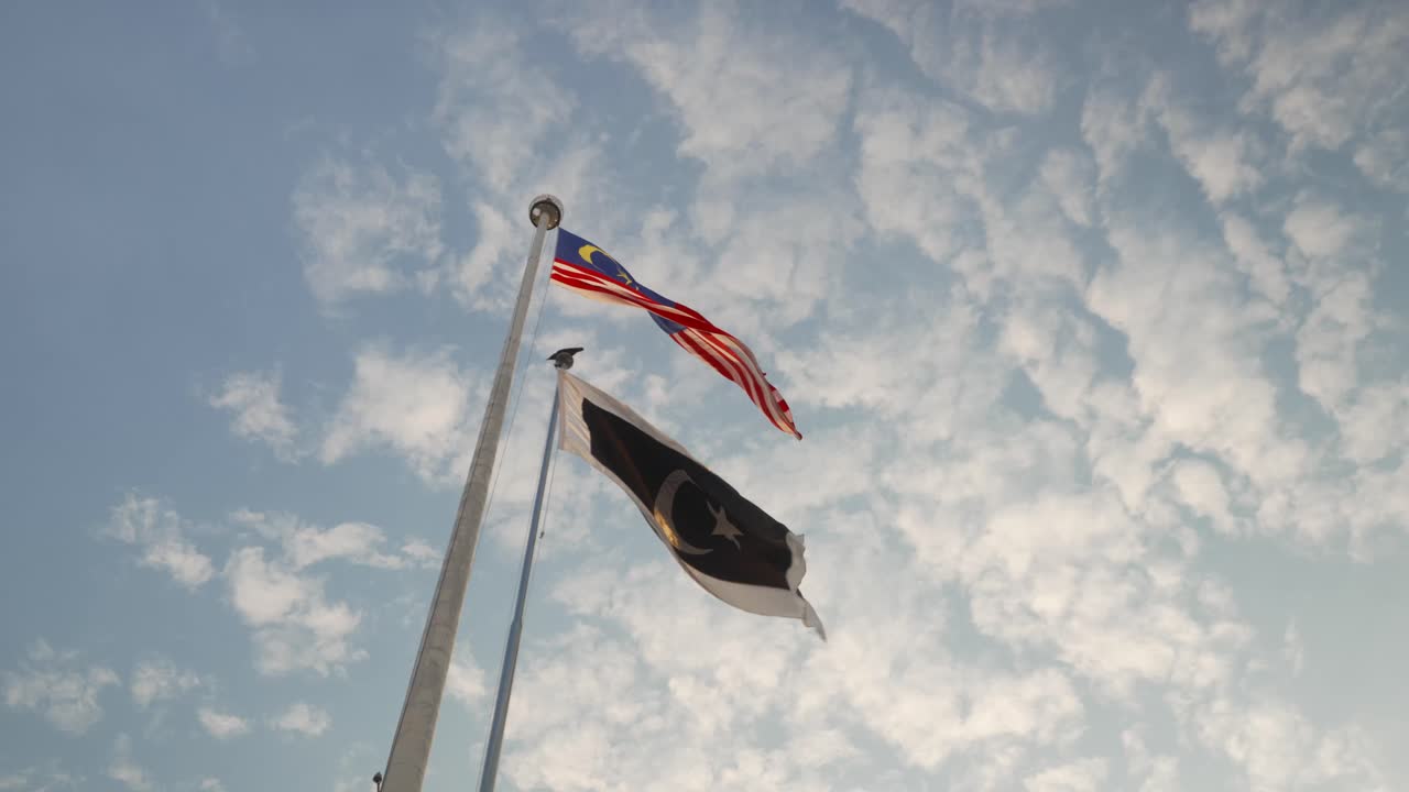 Il Jalur Gemilang sventola con orgoglio su un cielo luminoso, ripreso da un angolo drammatico dal basso verso l'alto