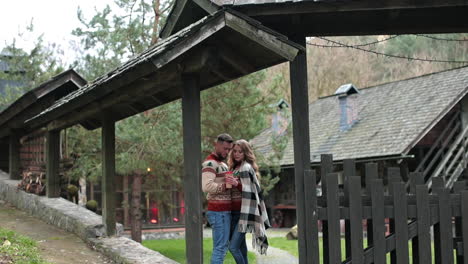 attractive couple in similar sweaters standing at the gates of a manor. autumn season in the countryside. cozy time-spending outside the big city.