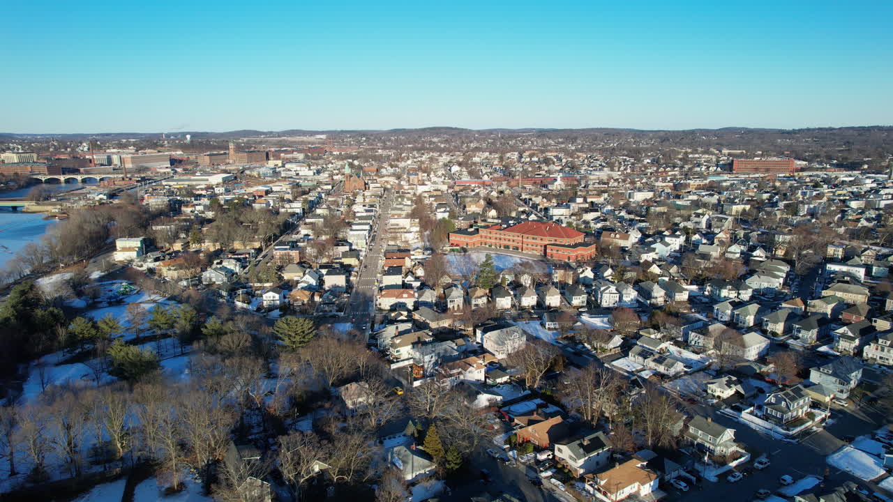 Sunny day in American town of Lawrence , Massachusetts. Aerial wide shot. Frozen Merrimack River in center of city. Neighborhood with houses and homes in winter season. Wetherbee school with red brick