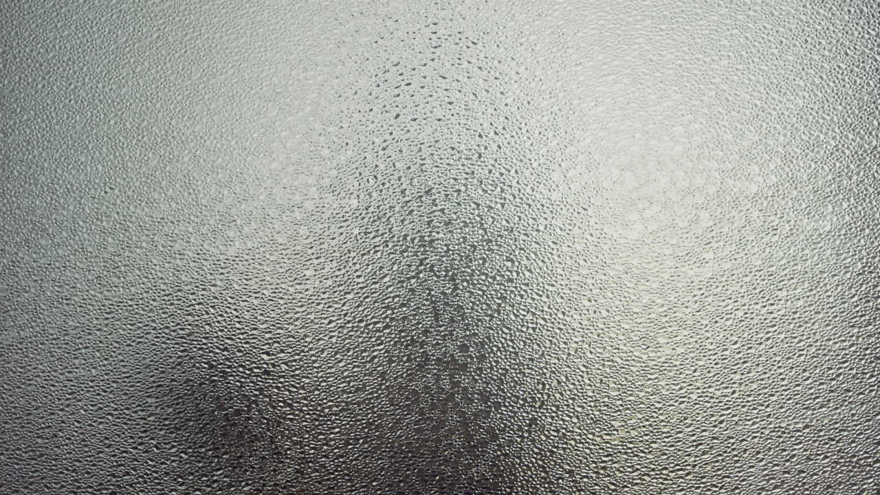 A female silhouette behind the frosted window touches the glass slowly