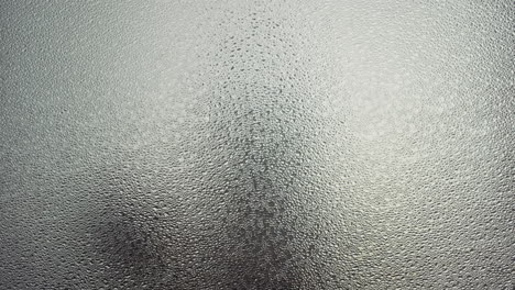 a female silhouette behind the frosted window touches the glass slowly