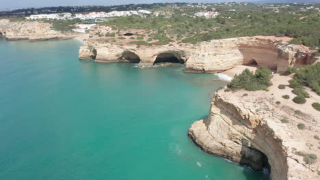 revelación aérea de una hermosa playa de arena rodeada de acantilados rocosos cerca de un mar azul