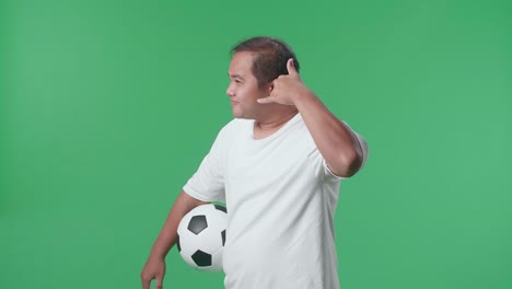 hombre haciendo un gesto telefónico con una pelota de fútbol