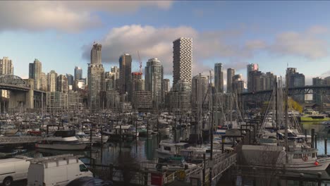 fisherman's wharf marina where small boats are docked anchored at a waterfront and the cityscape with high rise buildings in the background blue sky clouds bridge