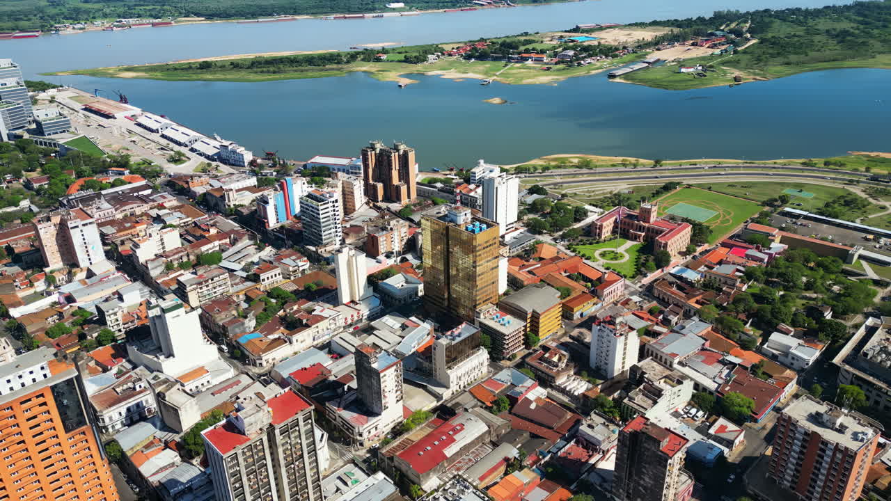 Aerial drone view of a Patagonian city with modern buildings, historical architecture, and a wide river flowing through the landscape