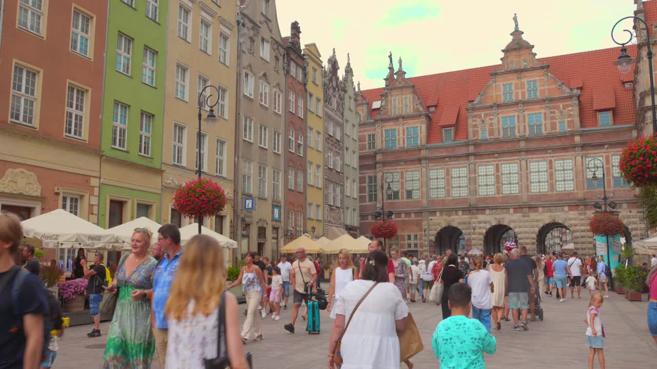 Stroll through the lively streets of Gdansk's Old Town, surrounded by colorful buildings and historic sites as visitors enjoy their day out under the sun.