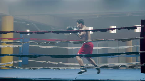 young male boxer doing shadow fight while training