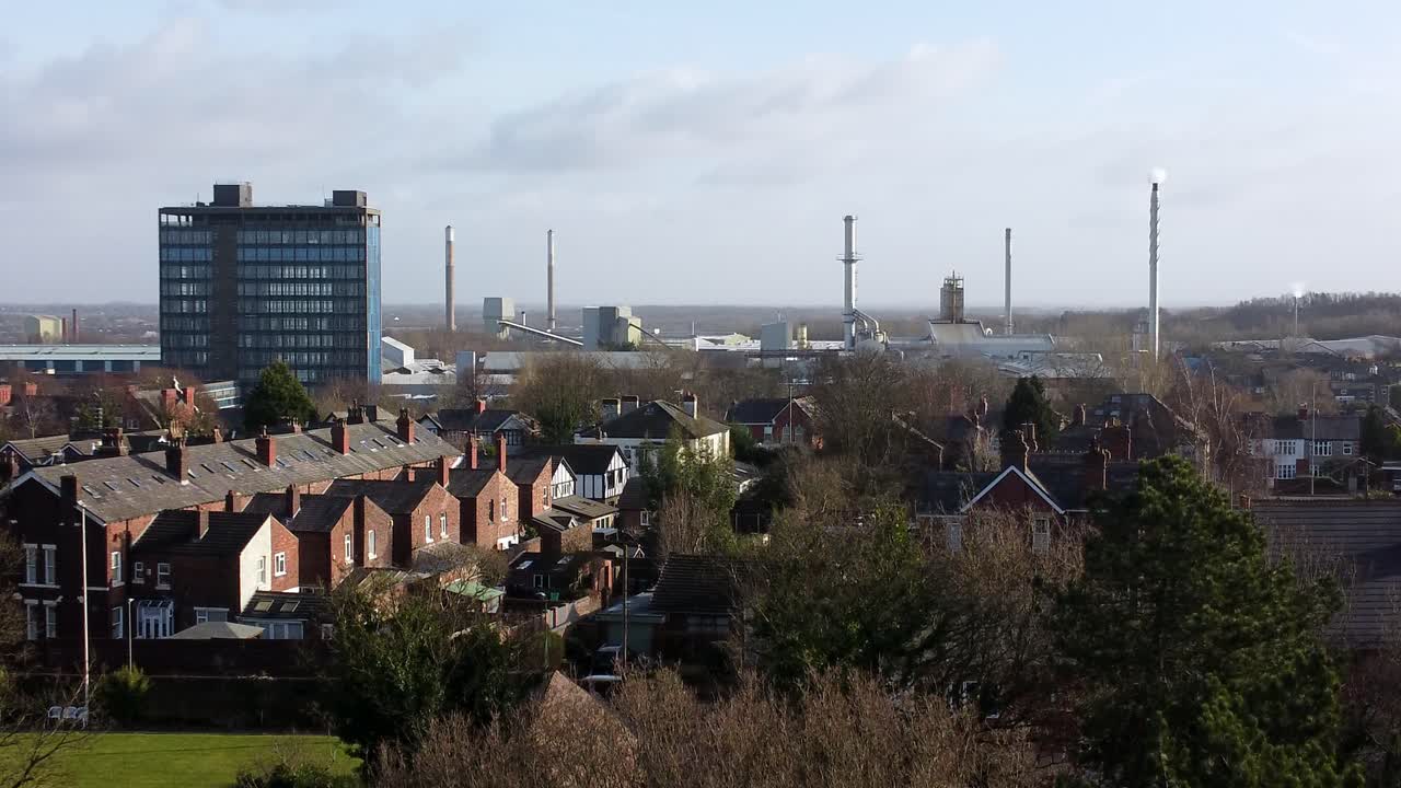 vista aérea ascendente sobre los árboles del parque hasta el paisaje urbano industrial con rascacielos azules pilkington, merseyside, inglaterra