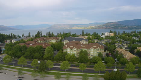 Drone-view-ascends-over-townhouses-and-condos-to-reveal-the-Okanagan-Lake-and-distant-mountains-in-Kelowna