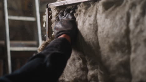 worker in gloves adjusts glass mineral insulation on detail