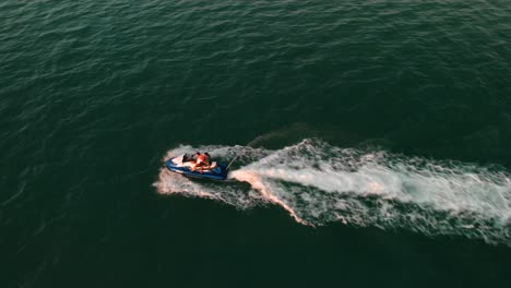 Drone-Cerca-Paso-Elevado-Un-Jetski-Con-Dos-Personas-A-Bordo,-Abu-Dhabi