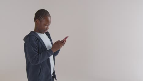 Studio-Portrait-Of-Excited-Boy-On-ASD-Spectrum-Gaming-On-Mobile-Phone-Against-White-Background-2