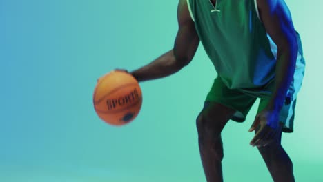 video of midsection of african american male basketball player bouncing ball on blue background