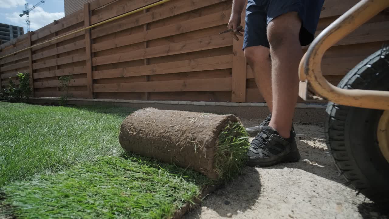 jardinero colocando césped en el patio privado con valla de madera
