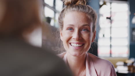 two young female friends meeting sitting at table in coffee shop and talking