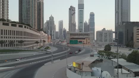 cars merging onto a larger motorway heading towards the urban centre at sunrise