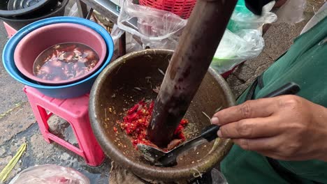 persona haciendo ensalada de papaya en un mortero