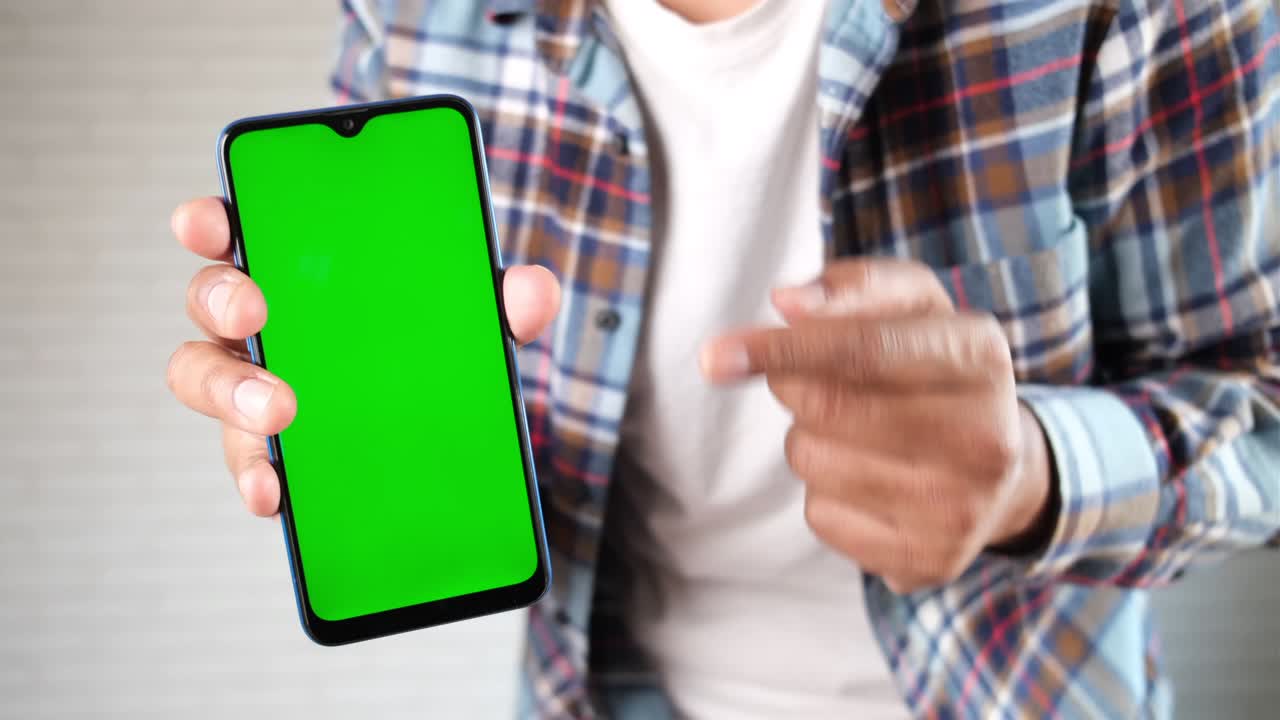 close up de la mano de un joven usando un teléfono inteligente con pantalla verde