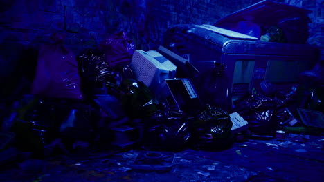 urban alley filled with discarded trash under blue lighting at night