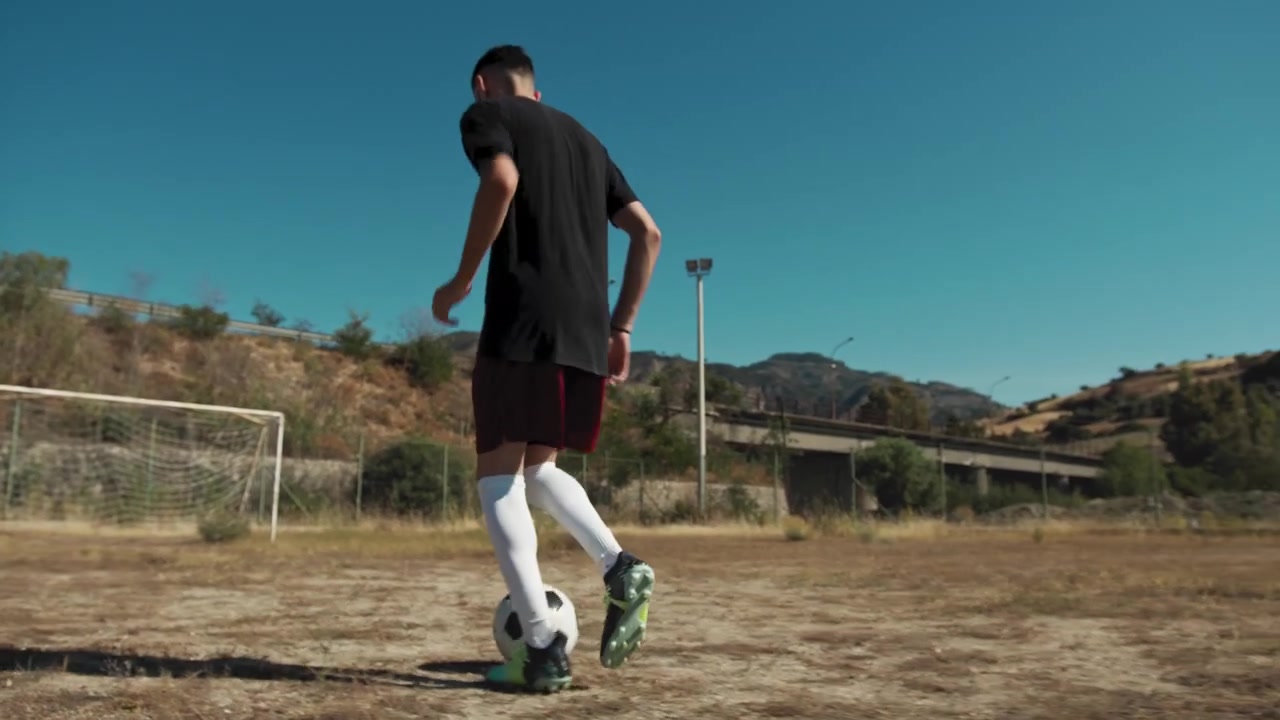 Giocatore che corre con il pallone allenandosi sotto il sole