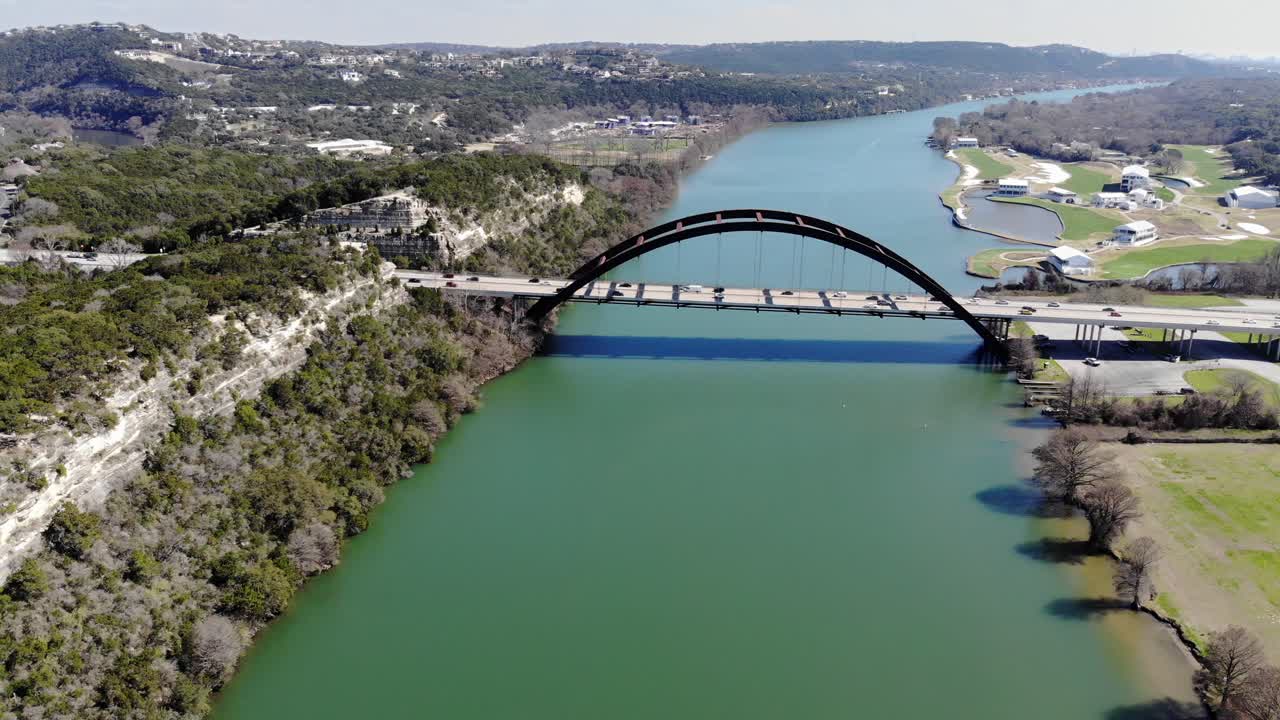Aerial Austin Pennybacker Bridge flying towards the bridge with good view of rock cliffs on the left and boat landing and golf course on the right.