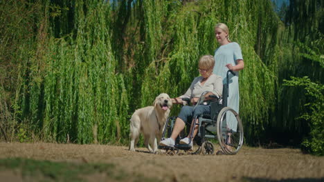 caregiver and elderly woman in wheelchair with dog in park