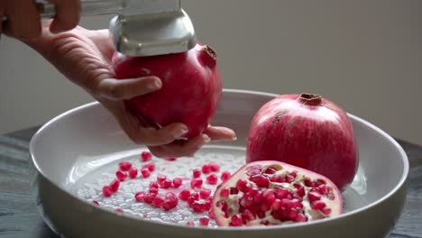golpeando la mitad de un gran jugo de granada roja que fluye de la granada sentado en un plato blanco antioxidantes saludables propiedades cardioprotectoras