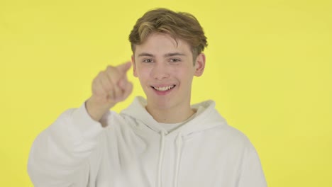 young man pointing at the camera on yellow background