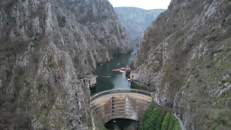 drone view of dam and building on treska river passing through matka canyon, athletes canoeing on the river