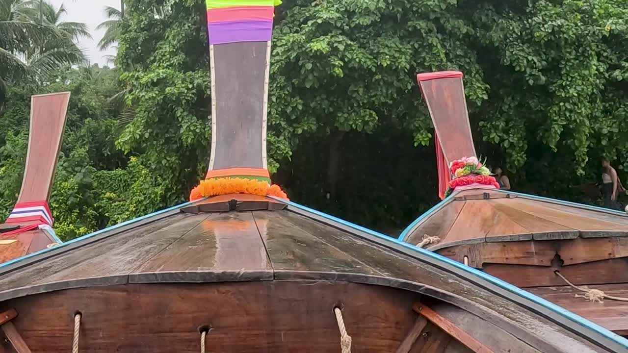 A vibrant longtail boat with colorful ribbons set against a backdrop of dense green foliage.