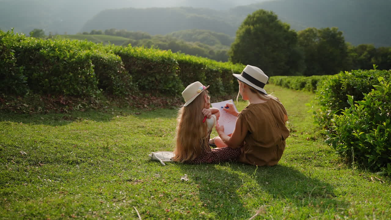 어머니 와 딸 이 차 농장 에서 그림 을 그리고 있다