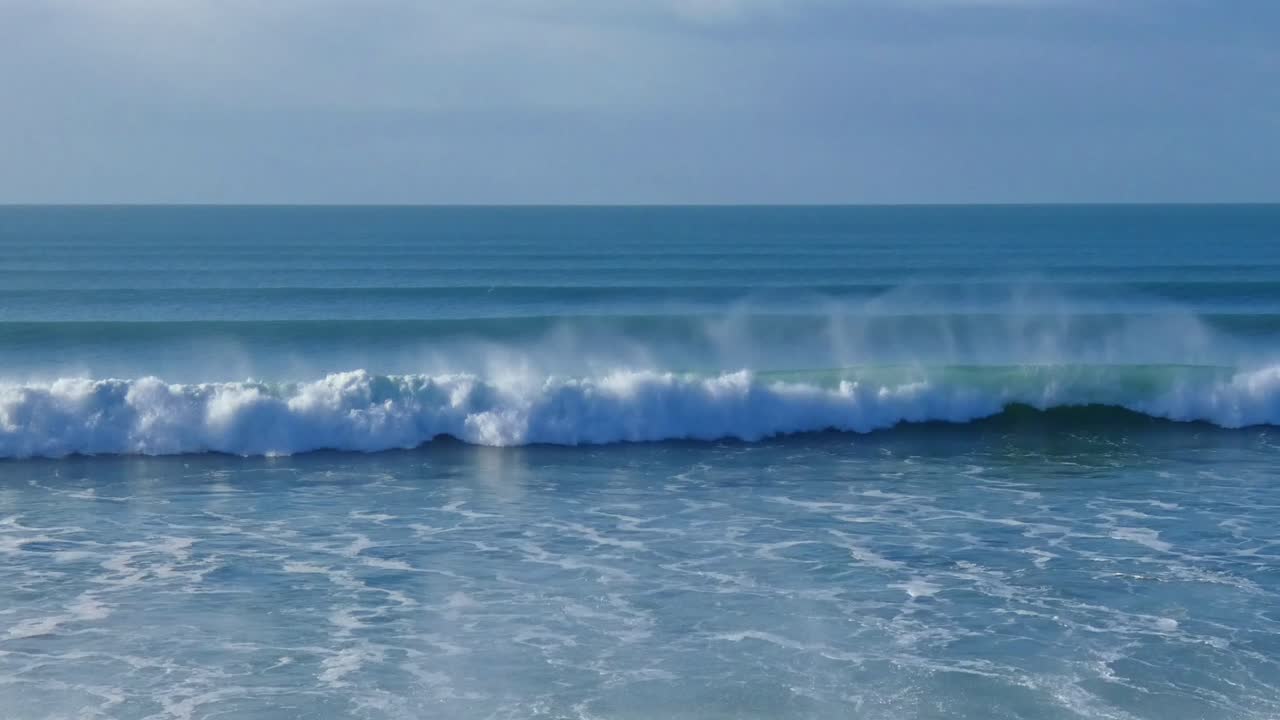 Lone surfer briefly appears between breaking waves on a beautiful mid-winter's morning - New Brighton Beach, Christchurch (New Zealand)
