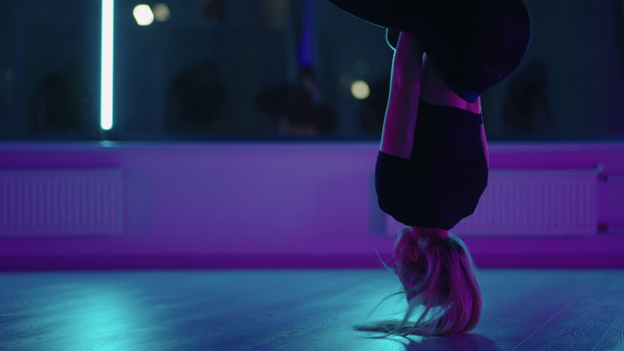 Woman hanging upside down and using yoga hammock swing while doing antigravity yoga exercise. Back view of beautiful young woman using hammock for doing pose of antigravity yoga