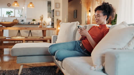 woman relaxing on sofa and texting on phone