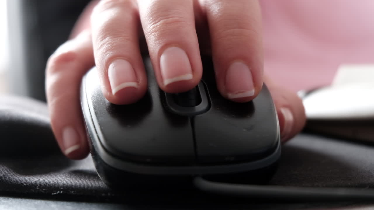 Close up of a woman clicking on a mouse while working on a computer