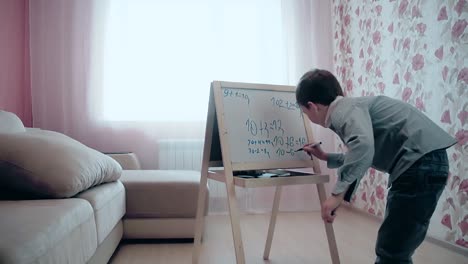 school boy writes numbers on easel