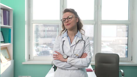 Portrait-Of-A-Beautiful-Female-Doctor-Standing-In-Her-Consulting-Room-And-Smiling-At-Camera