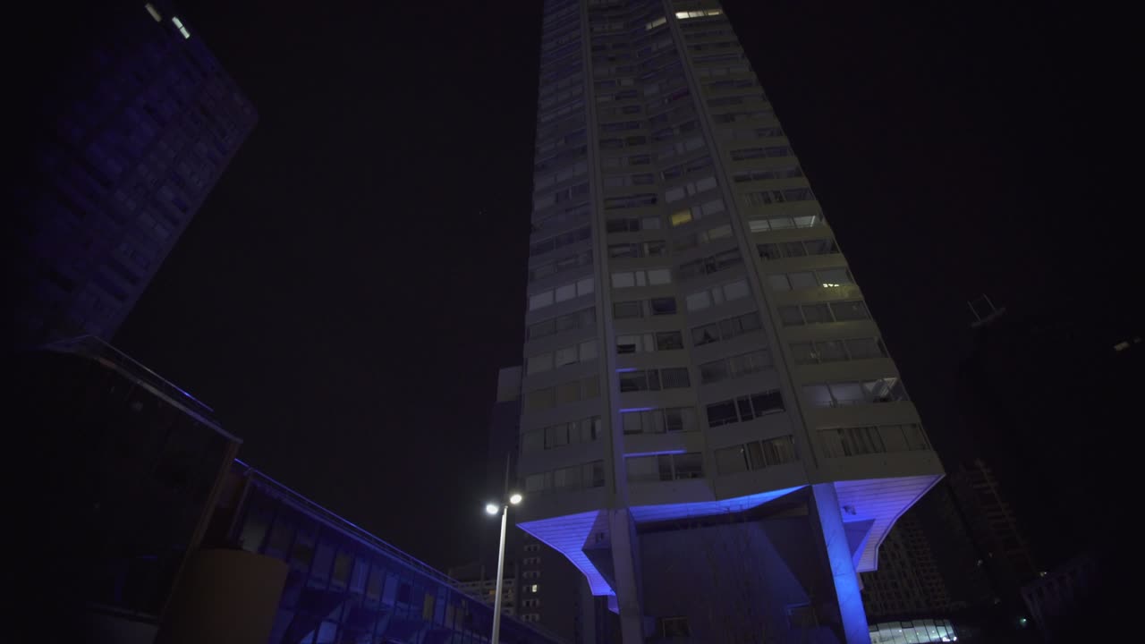 mirando hacia arriba rascacielos edificio moderno arquitectura azul por la noche con puntos de luz en el distrito de negocios en parís, movimiento lento steadicam bajo ángulo en el ojo de pez, pista lateral edificio moderno futurista.