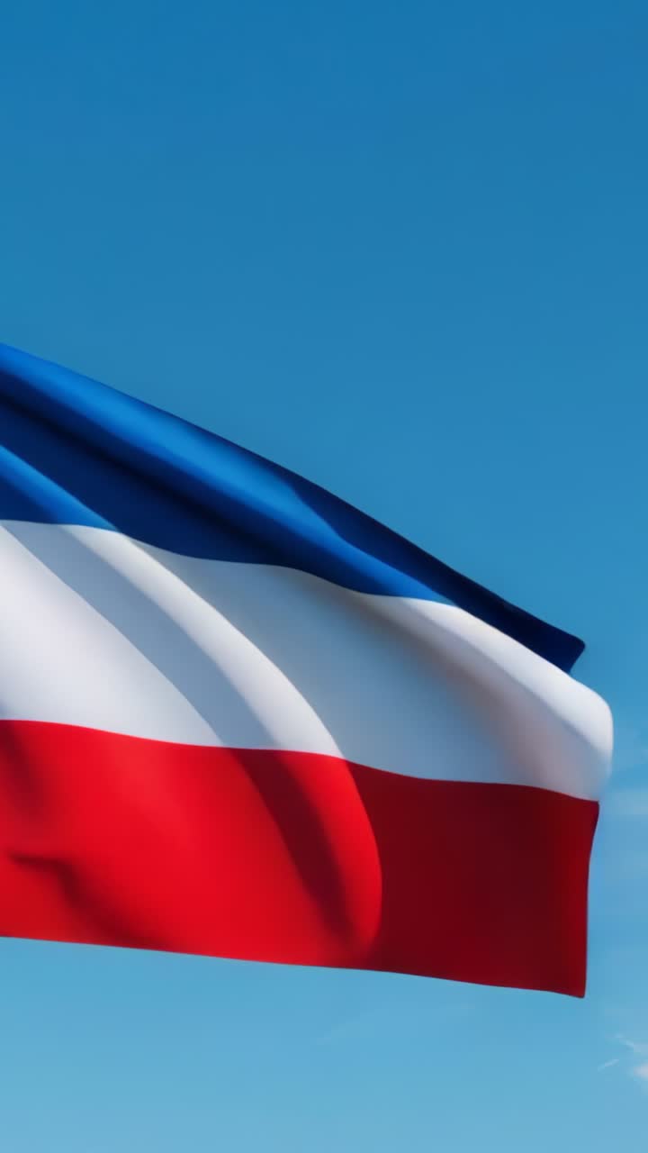 Vertical video: Blue white red flag fluttering under soft breeze in sky at sunset, with warm clouds