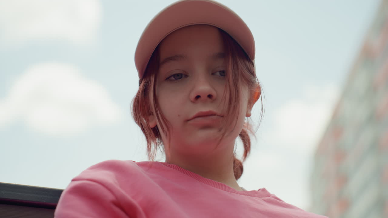 Teen Observing Urban Skyline Thoughtfully, Young Person Capturing Cityscape With Vibrant Attire, Young Individual With Pink Hat Thoughtfully Photographing Bustling City Skyline And Clouds