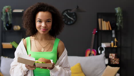 Una mujer comiendo una hamburguesa.