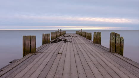 weathered wooden pier extending into calm sea at twilight